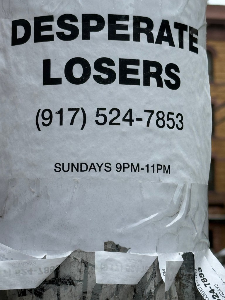 A flyer attached to a pole with bold text reading 'DESPERATE LOSERS', a phone number, and the hours 'SUNDAYS 9PM-11PM'.