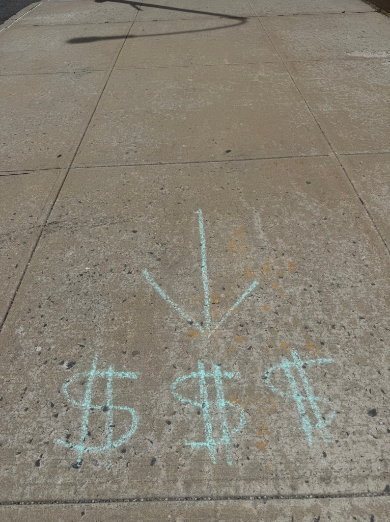 Chalk drawing on a sidewalk featuring three dollar signs with an arrow pointing downwards.
