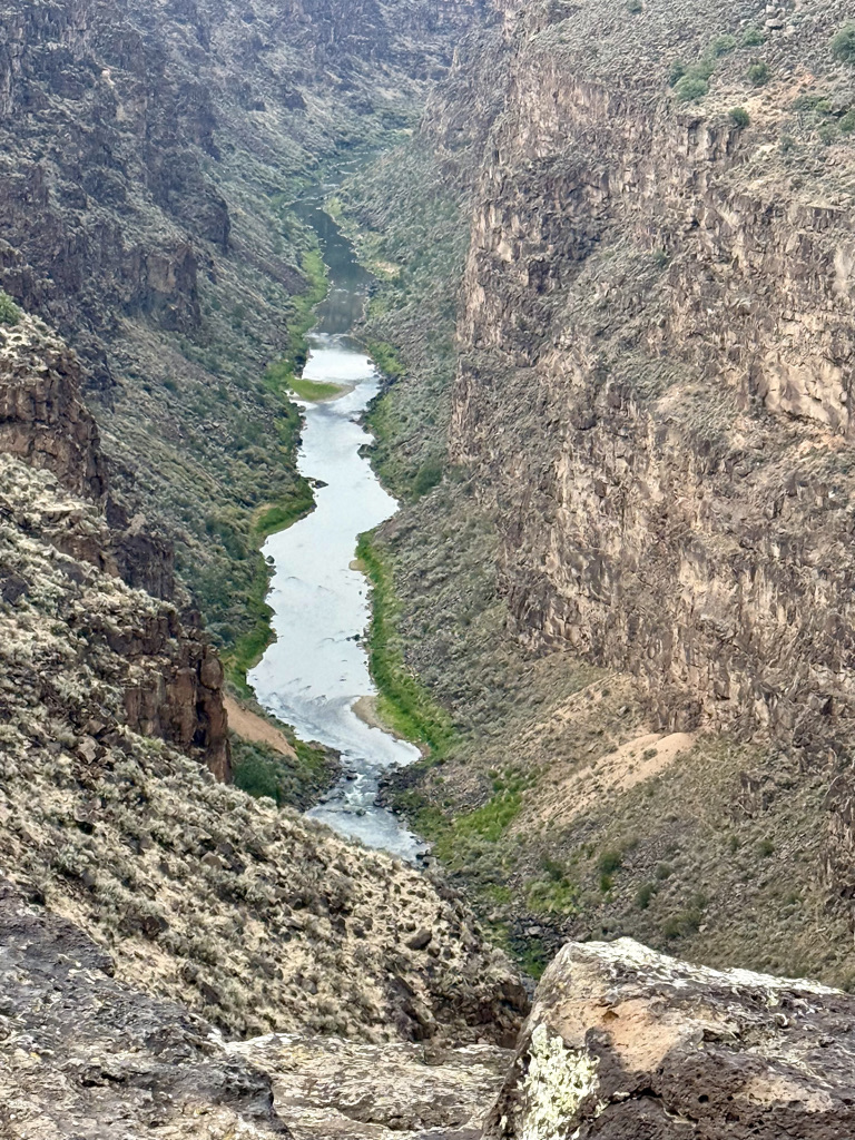 Aerial view of a winding river flowing through a steep canyon, surrounded by rocky cliffs and sparse vegetation.